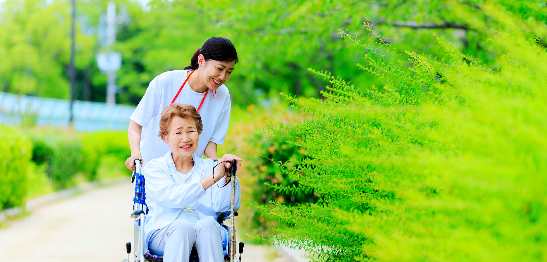 caregiver helping elder woman by pushing their wheelchair