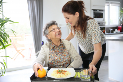 caregiver serving a meal to senior woman