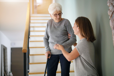 caregiver helping senior woman going down the stairs