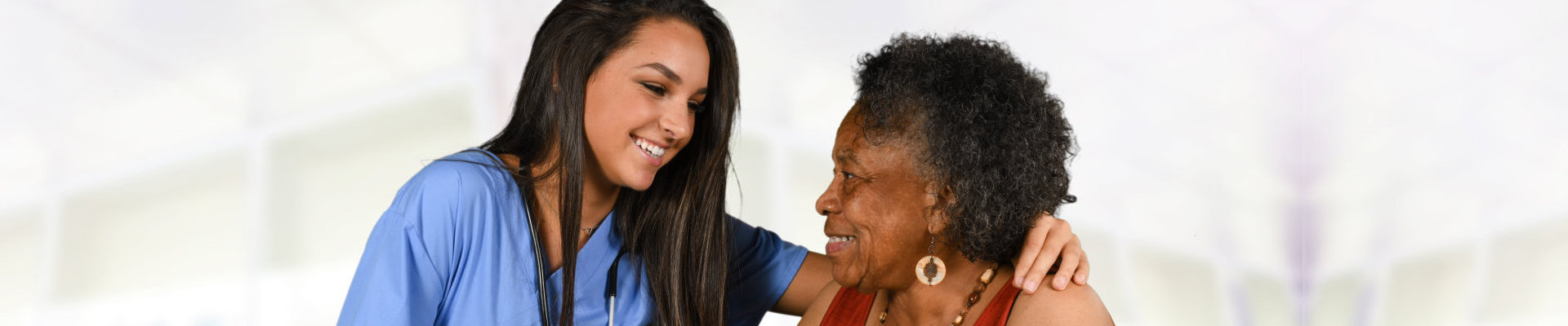 elder woman with lady caregiver smiling at each other