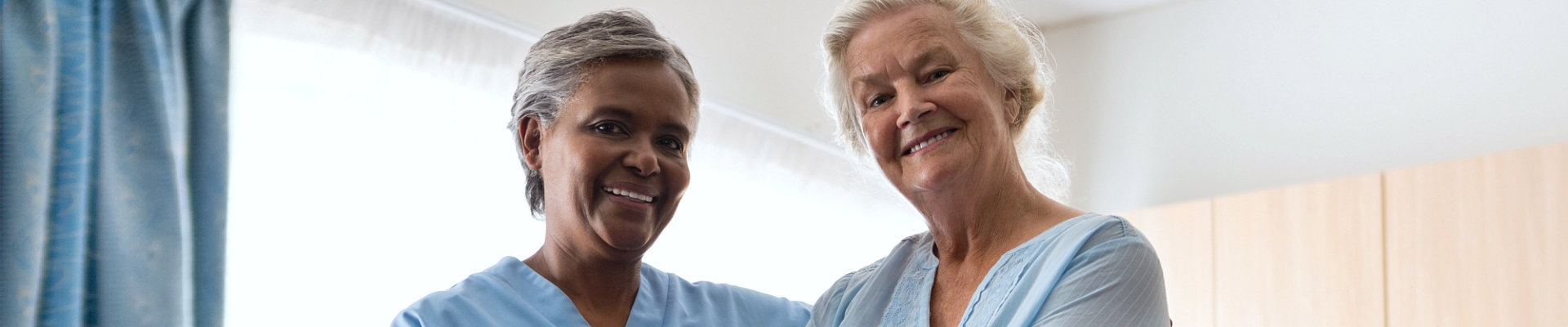 elder woman with adult caregiver smiling